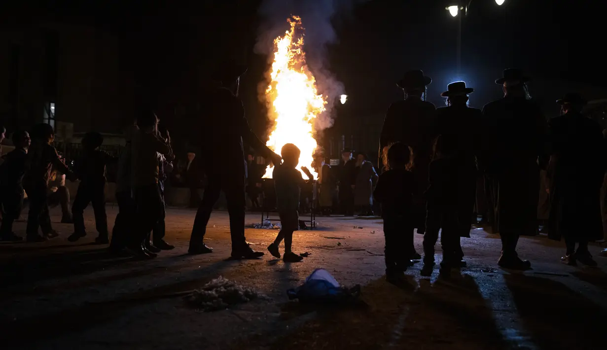 Yahudi Ultra-Ortodoks menari  di samping api unggun selama hari libur Yahudi perayaan Lag Ba'Omer di Bnei Brak, Israel, Kamis (29/4/2021). Liburan Lag Ba'Omer, menandai berakhirnya wabah yang dikatakan telah membinasakan orang Yahudi selama zaman Romawi. (AP Photo/Sebastian Scheiner)