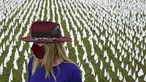 Seniman Suzanne Brennan Firstenberg berdiri di antara ribuan bendera putih yang ditanam untuk mengenang warga Amerika yang meninggal karena COVID-19 di dekat Stadion RFK di Washington, Selasa (27/10/2020). Instalasi seni publik ini disebut "In America, How Could This Happen.” (AP/Patrick Semansky)