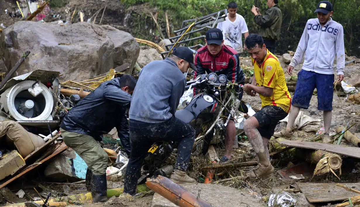 Warga mengangkat sepeda motor dari puing-puing setelah lereng bukit yang diguyur hujan runtuh menimpa rumah-rumah di Pereira, Kolombia, Selasa (8/2/2022). Hujan deras memicu tanah longsor menewaskan sedikitnya 14 orang dan melukai 35 lainnya. (AP Photo/Andres Otalvaro)