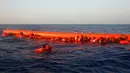 Sejumlah imigran memegang pelampung saat menunggu diselamatkan oleh petugas di lepas panti Libya, Laut Mediterania, Senin (29/8). Para penjaga pantai Italia berhasil menyelamatkan sekitar 6.500 imigran dari Eritrea dan Somalia. (REUTERS/Giorgos Moutafis)