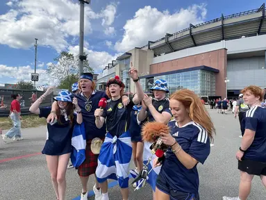 Suporter Skotlandia atau Tartan Army bernyanyi dan meneriakkan yel-yel di area fanzone Gillette Stadium, Foxborough, Amerika Serikat, Jumat (19/6/2026), menjelang laga melawan Maroko pada Piala Dunia 2026. Mereka mengenakan kilt tradisional, membawa bendera Saltire, serta berbagai atribut khas Skotlandia. (KLY Sports/Hery Kurniawan)