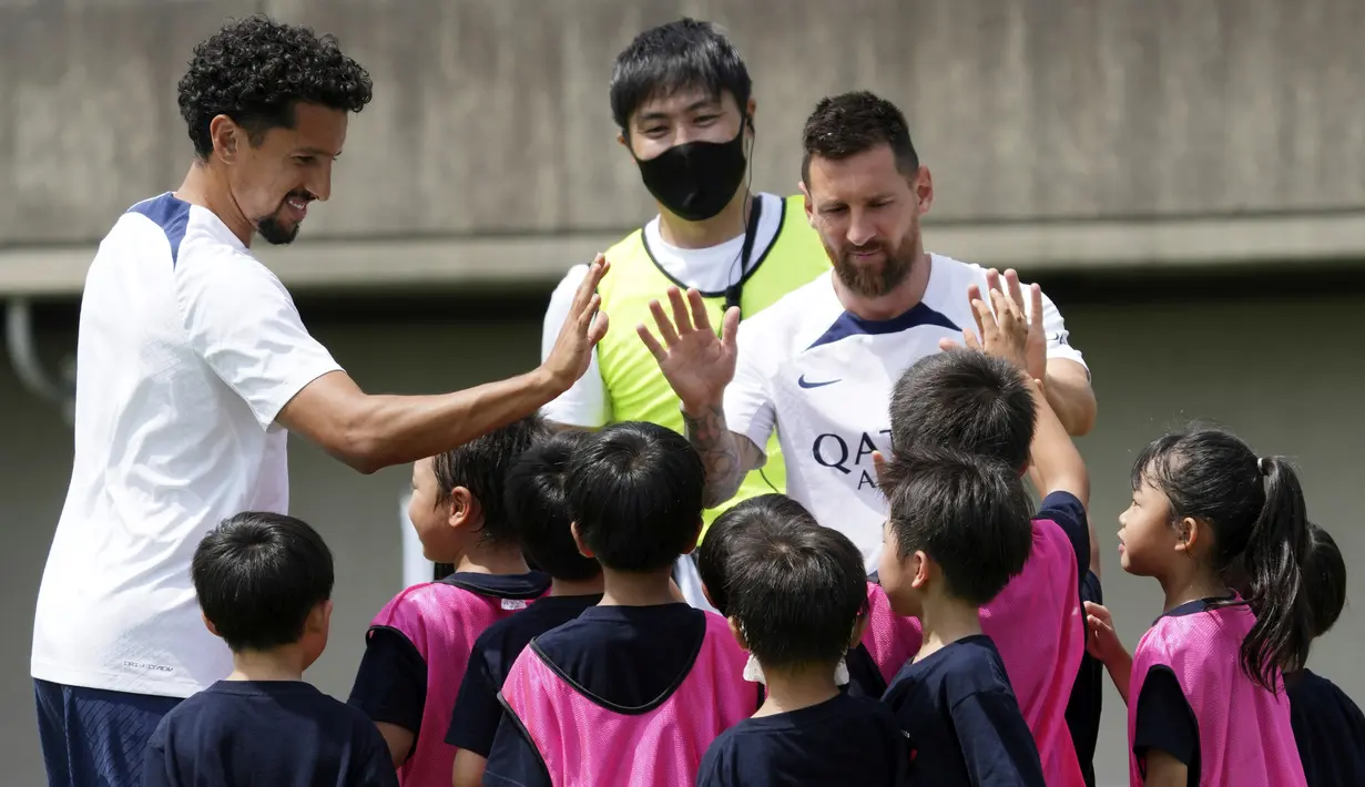 Pemain Paris Saint-Germain (PSG), Lionel Messi dan Marquinhos menyapa pesepak bola cilik saat memberikan pelatihan di Jepang. (AP/Eugene Hoshiko)