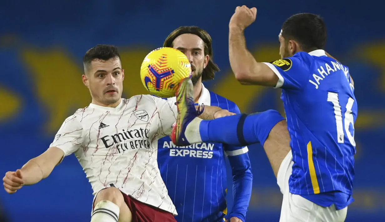 Pemain Arsenal, Granit Xhaka, berebut bola dengan pemain Brighton & Hove Albion, Alireza Jahanbakhsh, pada laga Liga Inggris di Stadion Amex, Selasa (30/12/2020). Arsenal menang dengan skor 1-0. (Mike Hewitt/Pool via AP)