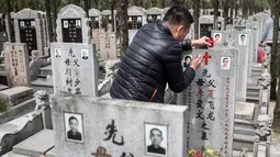 Seorang pria mengecat ulang batu nisan makam keluarga mereka saat festival Qingming di Shanghai (6/6). Festival tradisional Tiongkok ini dilaksanakan pada hari ke-104 setelah titik balik Matahari di musim dingin. (AFP/Johannes Eisele)