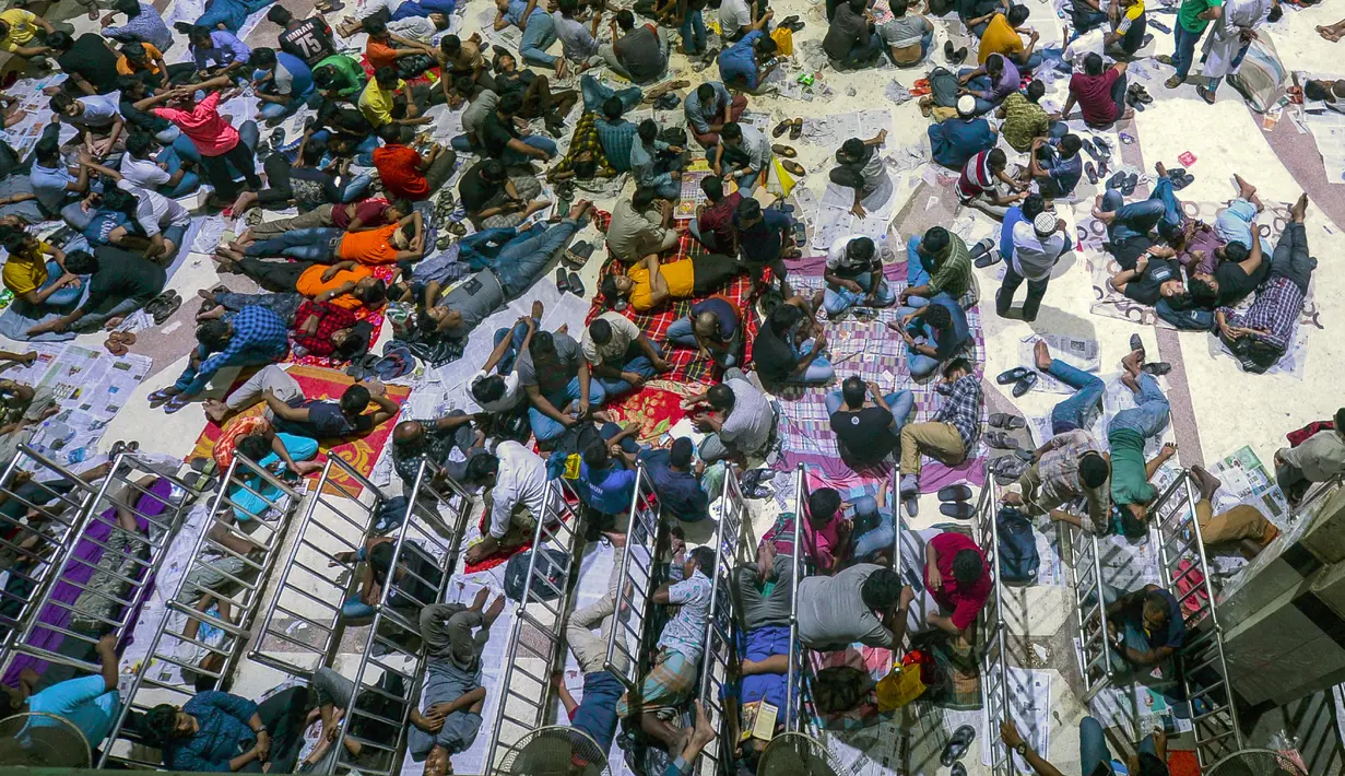Sejumlah calon pembeli duduk dan tidur di depan loket untuk mendapatkan tiket mudik lebaran di Stasiun Kereta Kamalapur, Dhaka, Kamis (23/5/2019). Pemudik Bangladesh rela antre berjam-jam dan bahkan menunggu jauh hari sebelum pembukaan loket tiket. (MUNIR UZ ZAMAN/AFP)