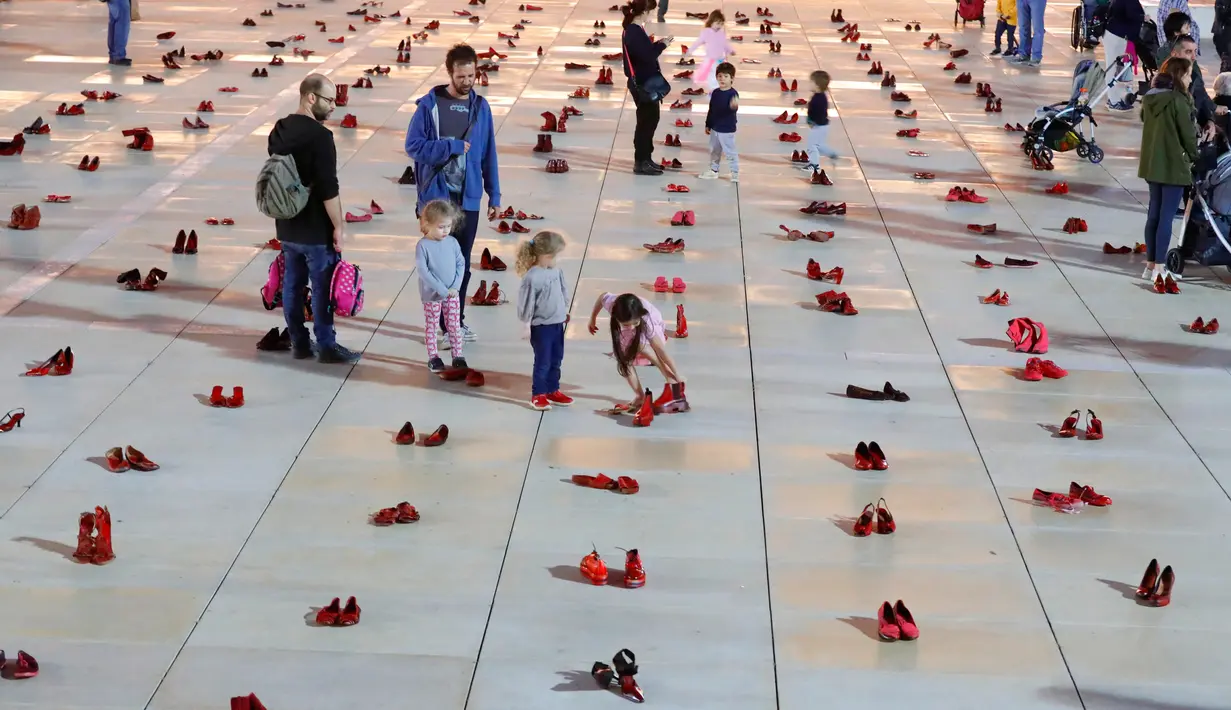 Orang-orang berjalan melewati instalasi ratusan sepatu merah untuk memprotes kekerasan terhadap perempuan di kota pesisir Tel Aviv, Selasa (4/12). Sepanjang tahun ini, 24 perempuan Israel tewas akibat tindakan kekerasan dalam rumah tangga. (JACK GUEZ/AFP)