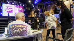 Pekerja Layanan Kesehatan Nasional menjawab pertanyaan di pusat vaksinasi Covid yang didirikan di klub malam Heaven di London, Minggu (8/8/2021). Heaven menjadi klub malam pertama di Inggris yang diubah sebagai pop-up pusat vaksinasi untuk mengajak kaum muda agar mau divaksin (AP/Alberto Pezzali)