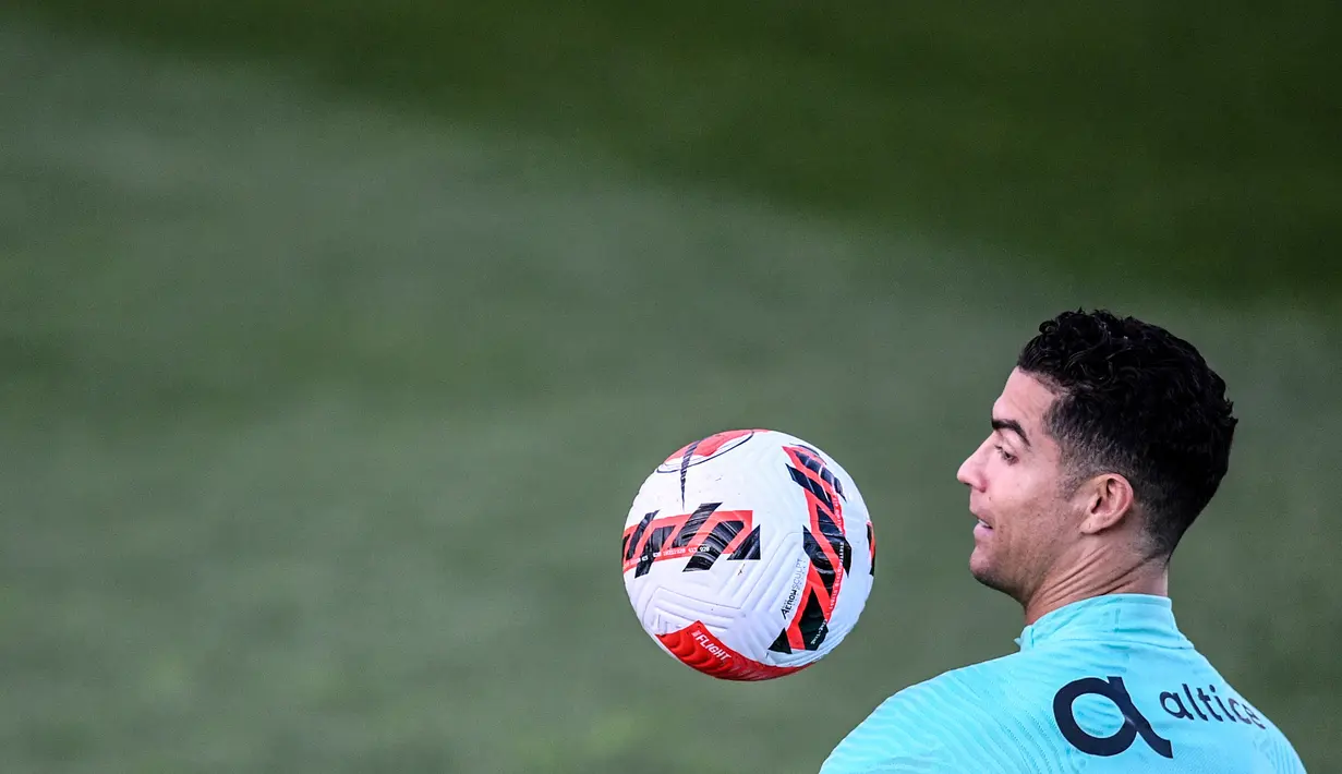 Pemain Portugal Cristiano Ronaldo menatap bola saat sesi latihan jelang menghadapi Turki pada pertandingan sepak bola kualifikasi Piala Dunia 2022 di kamp pelatihan Cidade do Futebol, Oeiras, Portugal, 21 Maret 2022. (PATRICIA DE MELO MOREIRA/AFP)