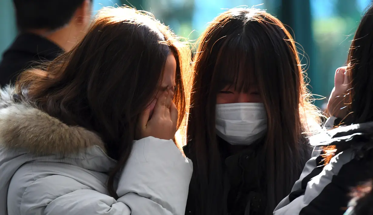 Tangis sejumlah fans saat memberikan penghormatan kepada Jonghyun SHINee di rumah duka Seoul Asan Hospital, Selasa (19/12). Pihak keluarga tidak akan melakukan autopsi dan menerima kematian Jonghyun sebagai akibat dari aksi bunuh diri (JUNG Yeon-Je / AFP)