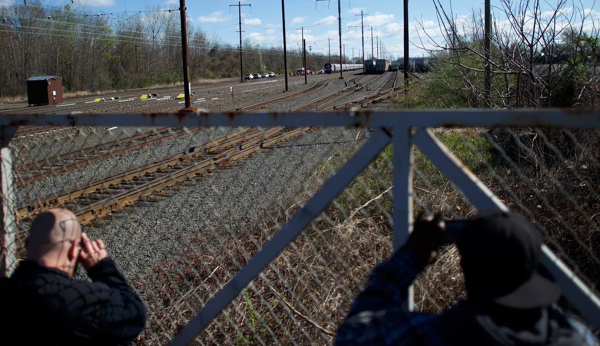 Warga mengambil gambar lokasi kereta Amtrak yang tergelincir setelah menabrak sebuah backhoe di dekat Philadelphia, Amerika Serikat, Minggu (3/4). Saat kejadian, kereta tersebut membawa 341 penumpang dan 7 kru. (Mark Makela/Getty Images/AFP)