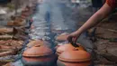 Seorang perempuan memasak ikan di pot tanah liat menggunakan kayu bakar di provinsi Ha Nam, Vietnam, Selasa (21/1/2020). Makanan lezat populer untuk Tahun Baru Imlek atau Tet di utara Vietnam itu dijual dengan masing-masing pot sekitar Rp 25ribu hingga Rp 80ribu. (Nhac NGUYEN / AFP)