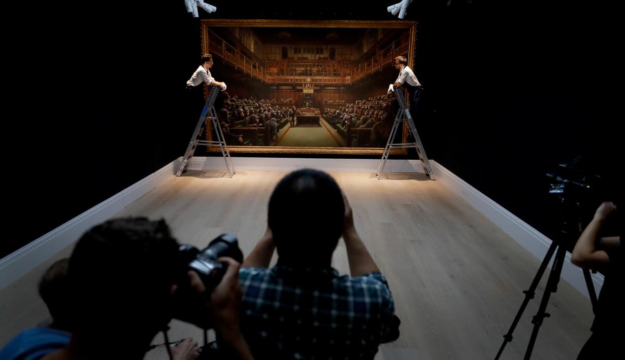Awak media mengambil gambar lukisan seniman jalanan Banksy yang dipajang di ruang lelang Sotheby, London, Jumat (27/9/2019). Sebelum dilelang di Museum Bristol, Inggris karya Banksy  tersebut masih dipajang di Sotheby's hingga 28 September. (AP/Kirsty Wigglesworth)