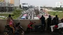 Warga melihat kendaraan terjebak kemacetan panjang di tol yang mengarah ke Bandara Soekarno-Hatta (Soetta), Tangerang, Banten, Selasa (10/11/2020). Kemacetan terjadi karena adanya penyambutan kepulangan pimipinan Front Pembela Islam (FPI) Rizieq Shihab. (Liputan6.com/Angga Yuniar)