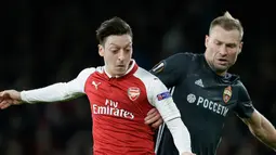 Pemain CSKA Moscow Aleksei Berezutski berebut bola dengan pemain Arsenal Mesut Ozil saat pertandingan Liga Eropa di stadion Emirates, London (5/4). Arsenal menang telak 4-1 atas klub Rusia, CSKA Moskow. (AP Photo / Tim Ireland)