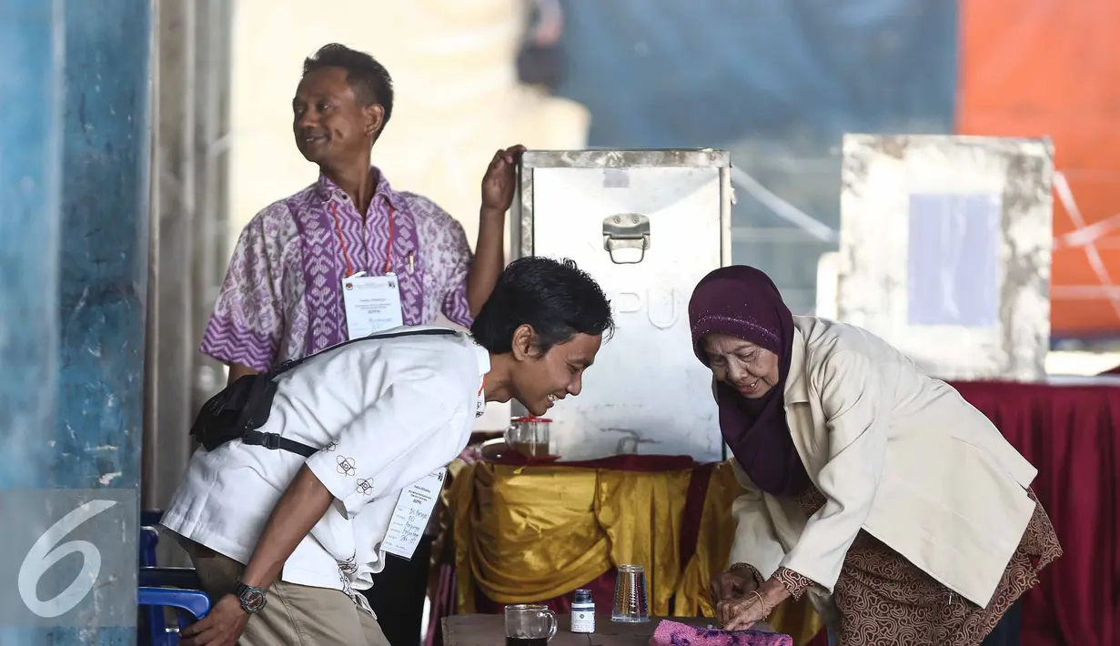 Panitia membantu warga yang menggunakan hak pilihnya dalam Pilkada DKI Jakarta di TPS 21 di bawah kolong jembatan tol akses Bandara, Petak Asem, Jakarta, Rabu (15/2). (Liputan6.com/Faizal Fanani)