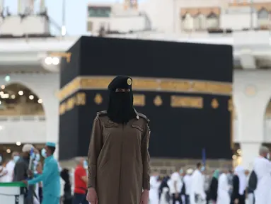 Seorang polisi wanita Saudi berjaga-jaga saat jemaah mengelilingi Ka'bah pada rangkaian ibadah haji di Masjidil Haram, Makkah, Selasa (20/7/2021). Kini, para personel perempuan bergabung dengan rekan-rekan pria mereka dalam menjaga kota suci selama musim haji. (Fayez Nureldine / AFP)
