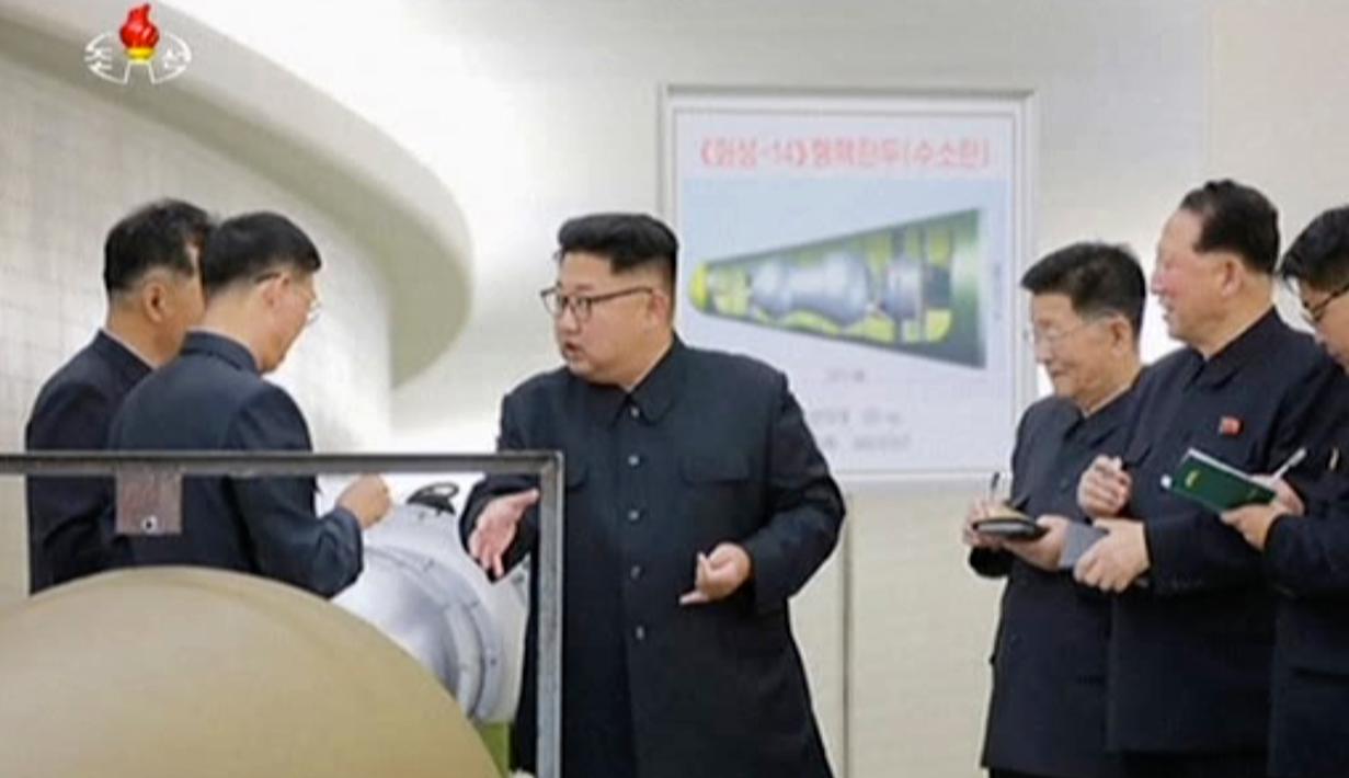 Pemimpin Korut, Kim Jong-un berbincang dengan para peneliti mengenai program senjata nuklir saat meninjau pembuatan bom hidrogen yang dapat dimasukkan ke dalam rudal balistik antarbenua pada 3 September 2017. (KRT via AP Video)