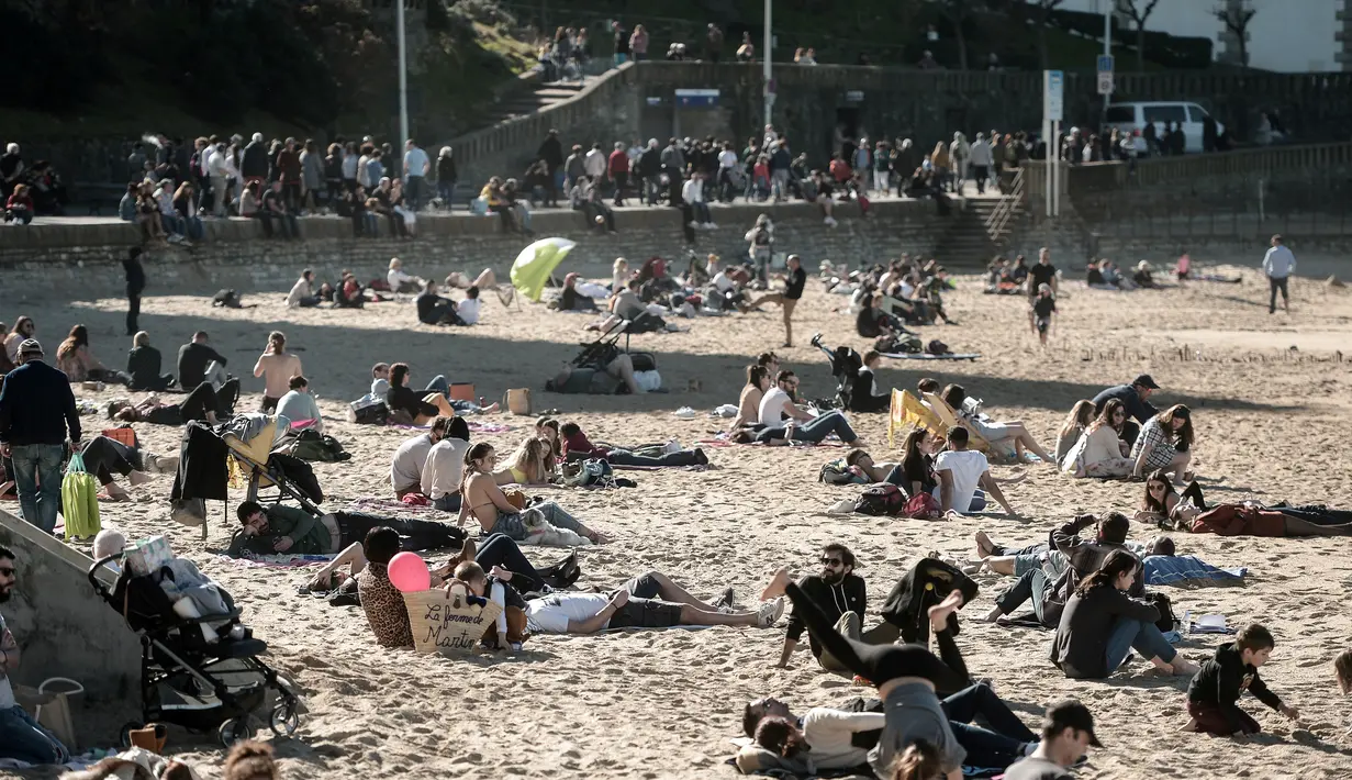 Penduduk dan turis duduk di pantai berpasir selama cuaca musim dingin yang hangat di Biarritz di Perancis barat (17/2). Kawasan pantai Biarritz yang berbatasan dengan Spanyol ini termasuk salah satu wilayah termahal di Prancis. (AFP Photo/Iroz Gaizka)
