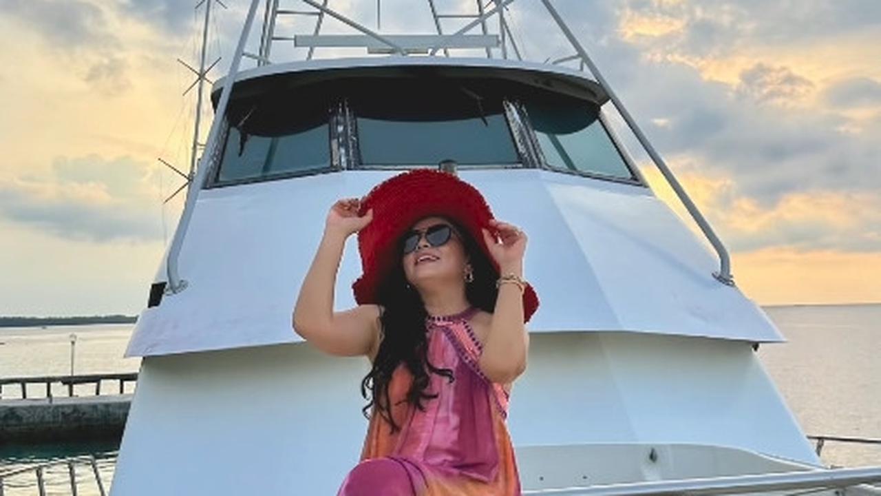 Mayang tak melewatkan kesempatan untuk berfoto di atas kapal mewahnya, memancarkan pesona sebagai sosialita dengan gaun dan topi yang memukau.
