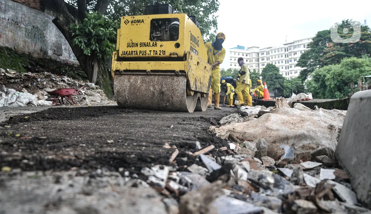 Petugas Sudin Bina Marga Jakarta Pusat memperbaiki jalan ambles di Jalan Inspeksi Kali Ciliwung, Kenari, Rabu (19/1/2022). Jalan yang berada di belakang RSCM tersebut ambles sepanjang 40 meter akibat terkikis oleh hujan deras kemarin sehingga menyulitkan akses warga. (merdeka.com/Iqbal S Nugroho)