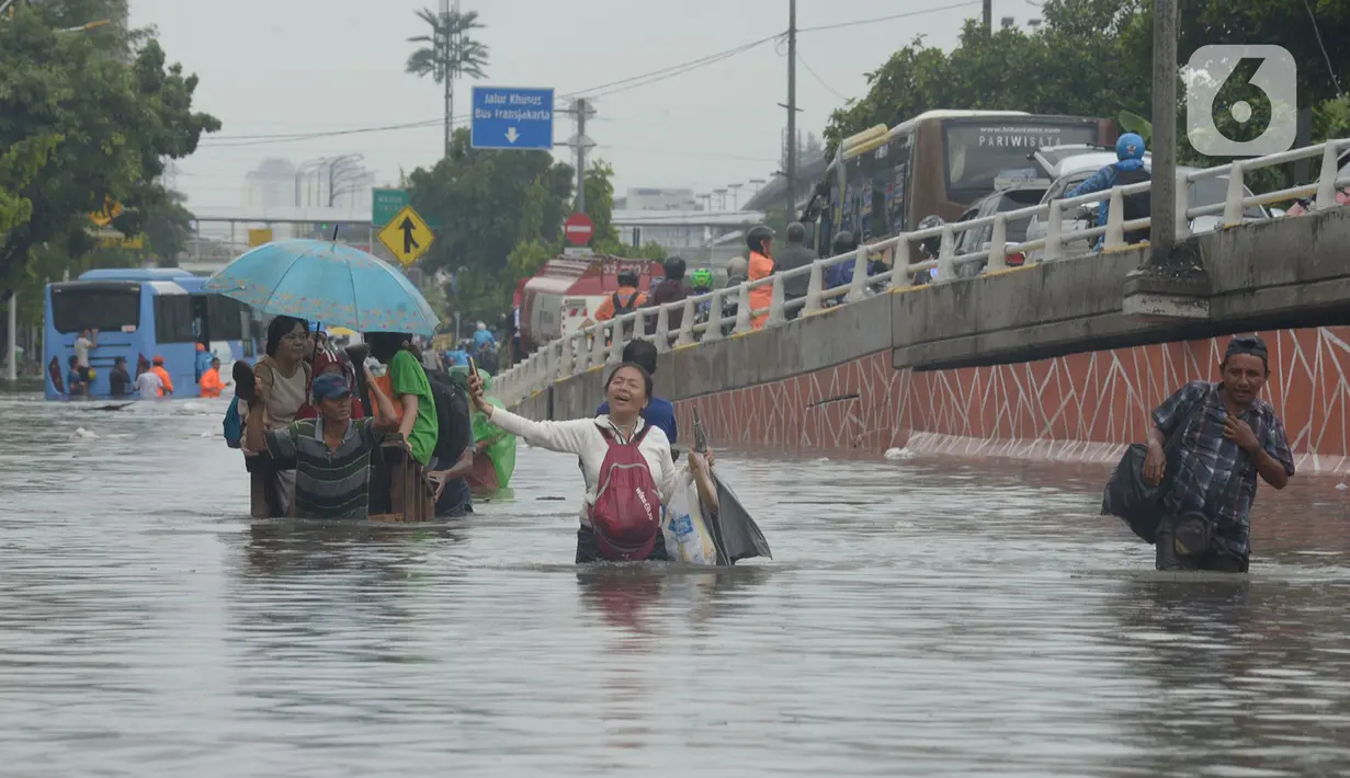 Warga RW 04 Kelurahan Jelambar melintasi banjir di Jakarta, Rabu (1/1/2020). Hujan yang turun saat pergantian tahun baru 2019-2020 menyebabkan sejumlah titik di kawasan Grogol terendam banjir. (merdeka.com/Imam Buhori)