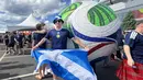 Suporter Skotlandia berpose sambil membentangkan bendera Saltire di depan replika bola resmi Piala Dunia 2026 di area fanzone Gillette Stadium, Foxborough, Amerika Serikat, Jumat (19/6/2026), menjelang laga melawan Maroko. Beragam atribut khas yang dikenakan Tartan Army turut menyemarakkan atmosfer Piala Dunia 2026. (KLY Sports/Hery Kurniawan)