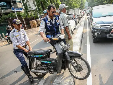 Petugas Dishub mengangkut sepeda motor saat melakukan penertiban parkir liar di atas trotoar kawasan KH Wahid Hasyim, Jakarta, Selasa (1/8). Penertiban dalam rangka 'Bulan Patuh Trotoar' itu untuk mengembalikan fungsi trotoar. (Liputan6.com/Faizal Fanani)