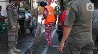 Petugas Satpol PP memberikan sanksi menyapu kepada warga yang tidak menggunakan masker di kawasan Pasar Baru, Jakarta, Jumat (21/8/2020). Sanksi tersebut dilakukan sebagai bagian dari upaya pencehagan penyebaran virus covid-19. (Liputan6.com/Immanuel Antonius)