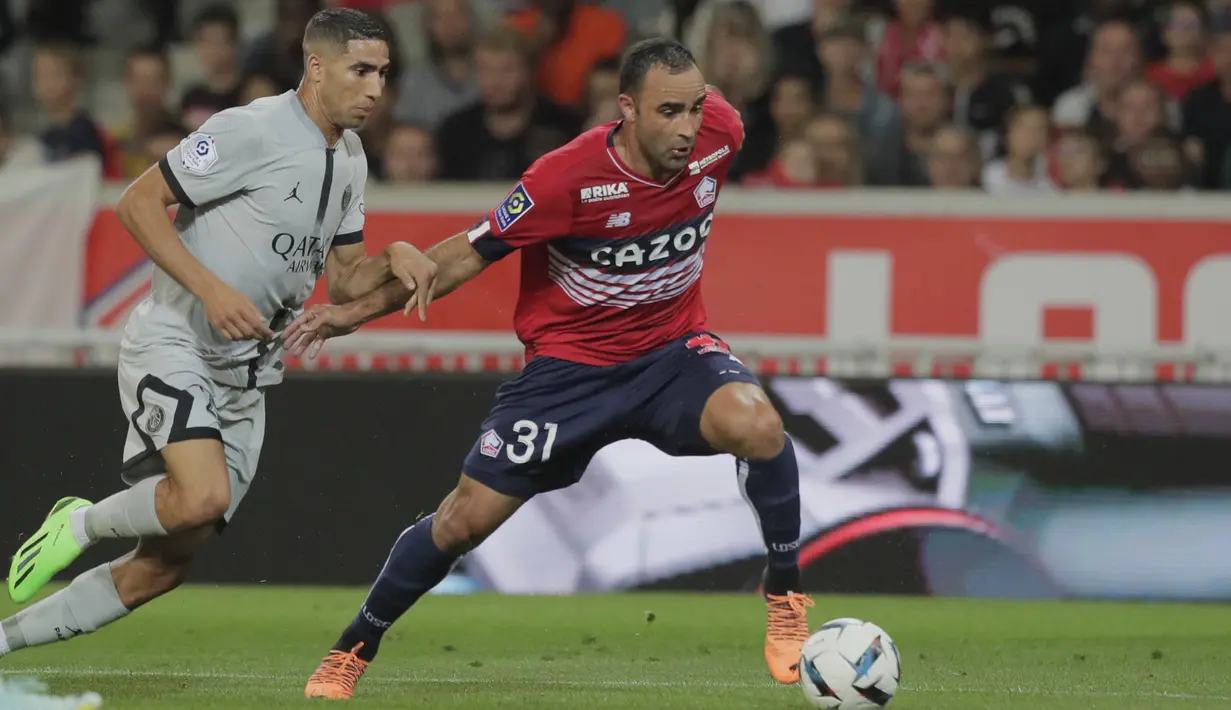 Bek Paris Saint-Germain (PSG) Achraf Hakimi berusaha merebut bola dari bek Lille Ismaily pada pekan ketiga Ligue 1 (Liga Prancis) 2022/2023  di Stadion Pierre-Mauroy, Senin (22/8/2022) dini hari WIB.  PSG berpesta gol ke gawang Lille dengan skor 7-1. (AP Photo/Michel Spingler)