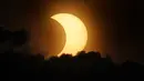 Matahari yang mengalami gerhana sebagian muncul dari balik awan saat terbit di atas Manhattan di New York, Kamis (10/6/2021). NASA menjelaskan beberapa wilayah Bumi yang bisa melihat fenomena tersebut yakni di bagian Kanada, Greenland, dan Rusia utara. (AP Photo/Seth Wenig)
