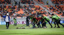 Sejumlah petugas menyingkirkan air yang menggenangi lapangan Jakarta International Stadium (JIS) jelang laga perempat final Piala Dunia U-17 2023 antara Timnas Brasil U-17 melawan Timnas Argentina U-17, Jumat (24/11/2023). (Bola.com/Bagaskara Lazuardi)