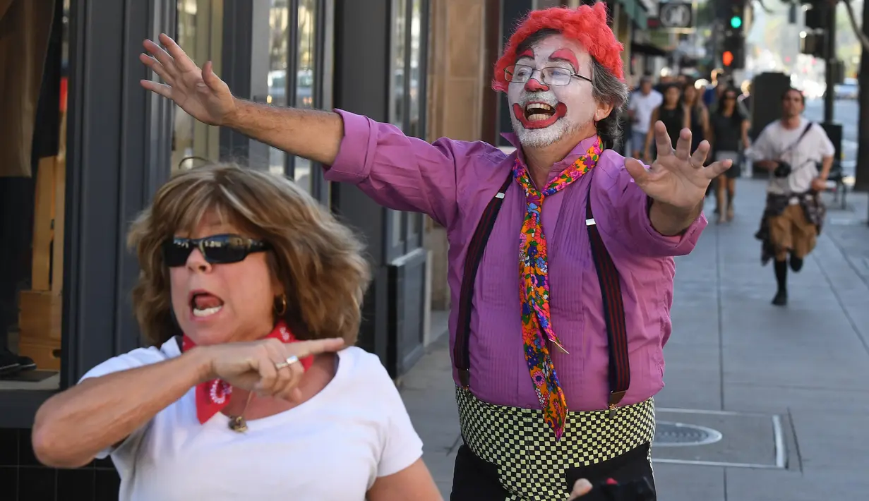 Peserta berdandan seperti badut mengejar pejalan kaki selama 'Running of the Clowns' di Pasadena, California pada 21 Oktober 2018. Lari dikejar kawanan badut ini merupakan parodi yang mengolok-olok lomba dikejar banteng di Spanyol. (Mark RALSTON/AFP)