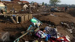 Warga tertidur ketika tengah melakukan evakusi barang setelah diterjang banjir bandang di Kampung Cimacan, Kecamatan Tarogong, Kabupaten Garut, Kamis (22/9). Data sementara Basarnas Jabar, 57 rumah hanyut dan 633 rumah terendam. (Liputan6.com/Johan Tallo)