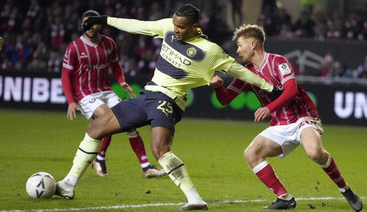 Pemain Manchester City, Manuel Akanji (kiri) berebut bola dengan pemain Bristol City, Sam Bell pada laga putaran kelima Piala FA 2022/2023 melawan Bristol City di di Ashton Gate, Rabu (1/3/2023) WIB. Sebagai pemain yang berposisi sebagai bek, Akanji mampu tampil solid dan menjaga daerah pertahanan The Cityzens tanpa kebobolan. (AP Photo/Kirsty Wigglesworth)