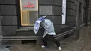 Warga menggunakan payung untuk berlindung dari hujan dan angin di kawasan The Bund, di Shanghai, Senin, 10 Agustus 2026. (AFP/ Hector Retamal)