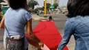 Warga membentangkan karpet merah di salah satu ruas jalan di distrik Magdalena del Mar, Lima, Peru, (2/7). Warga melakukan ini untuk menggugah kesadaran warga perkotaan agar bisa menghormati pejalan kaki. (REUTERS / Guadalupe Pardo)