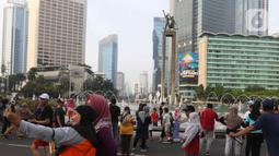 Warga berswafoto di kawasan bundaran HI, Jakarta, Minggu (12/6/2022). Car Free Day di kawasan Sudirman-Thamrin dimanfaatkan warga untuk berolah raga dan ber foto-foto. (Liputan6.com/Herman Zakharia)