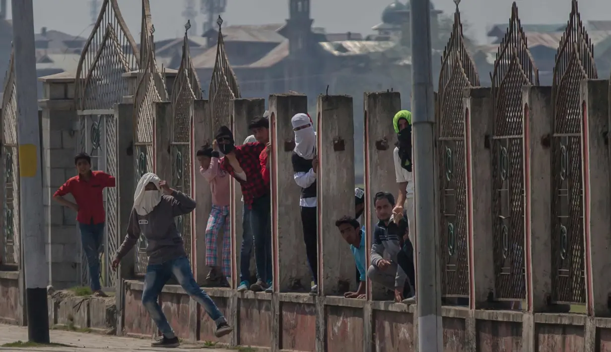 Para pemuda Kashmir berlindung saat bentrok dengan tentara paramiliter India di Srinagar, Kashmir, India, (1/4). Pengunjuk rasa memprotes menyusul tewasnya delapan pemberontak dalam bentrokan dengan pasukan pemerintah. (AP Photo / Dar Yasin)