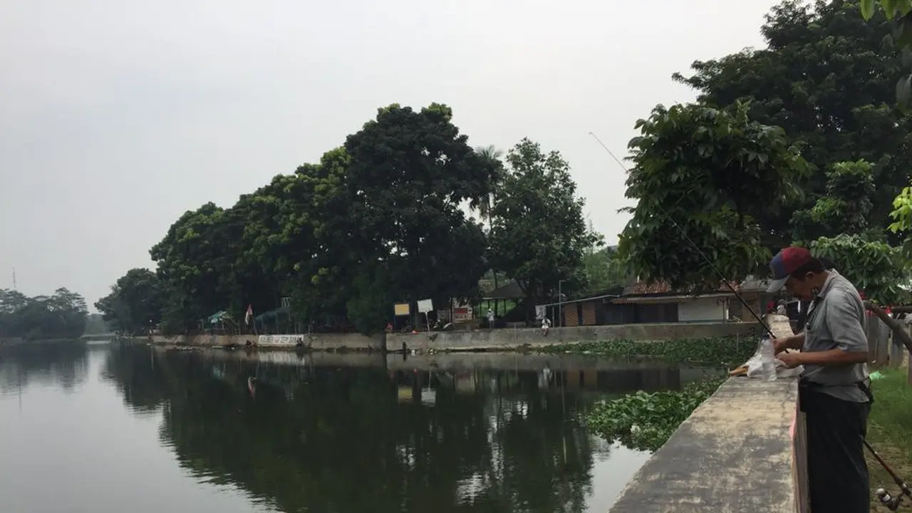 Alwadi, pedagang masker keliling di Pamulang, Tangerang Selatan, mengisi waktu dengan memancing di hari pertama penerapan PSBB di Kota Tangsel, Banten, Sabtu (18/4/2020)