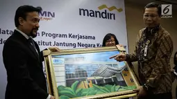 Chief Operating Officer IJN Kuala Lumpur Akmal Arief Mohamed Fauzi memberi lukisan kepada Direktur Retail Banking Bank Mandiri Tardi saat penandatanganan perjanjian kerjasama di Jakarta, Rabu (6/9). (Liputan6.com/Angga Yuniar)
