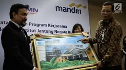 Chief Operating Officer IJN Kuala Lumpur Akmal Arief Mohamed Fauzi memberi lukisan kepada Direktur Retail Banking Bank Mandiri Tardi saat penandatanganan perjanjian kerjasama di Jakarta, Rabu (6/9). (Liputan6.com/Angga Yuniar)