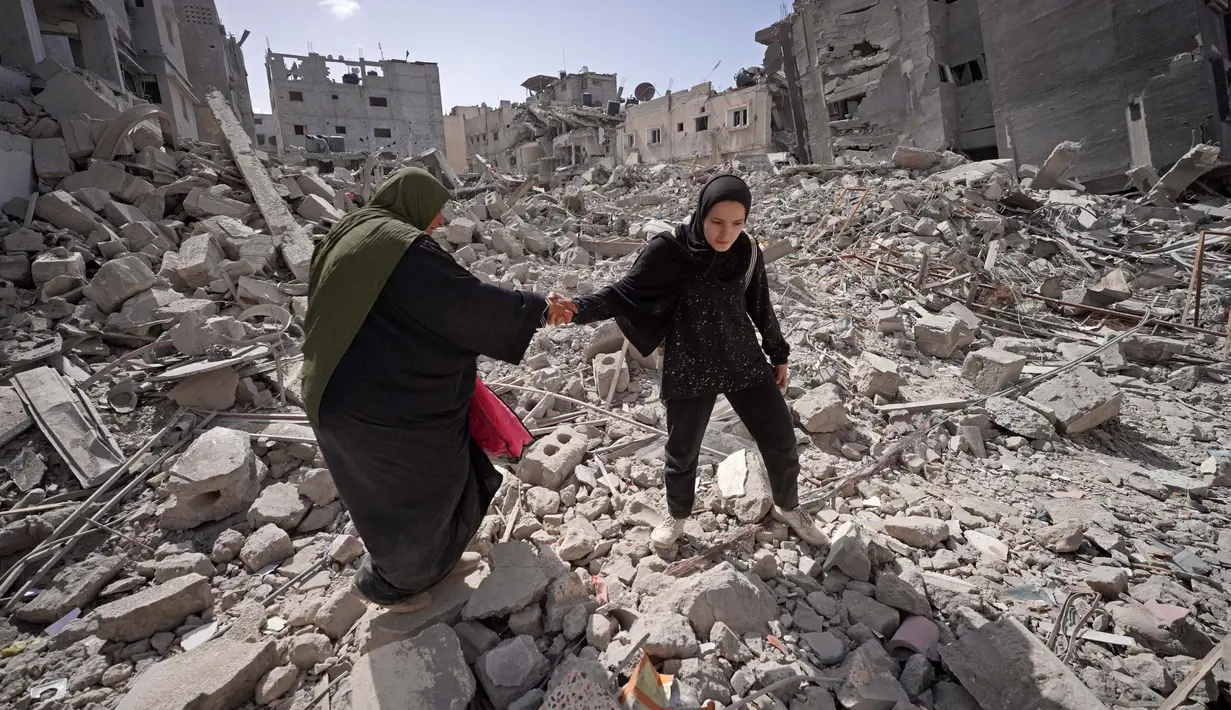 <p>Warga Palestina berjalan melewati puing-puing rumah yang hancur di Khan Yunis, Jalur Gaza Selatan pada 6 Maret 2024. Kementerian Kesehatan Gaza juga mengungkap sebanyak 60 ribu wanita hamil di wilayah tersebut menderita kekurangan gizi dan dehidrasi akibat perang Israel. (Foto oleh AFP)</p>