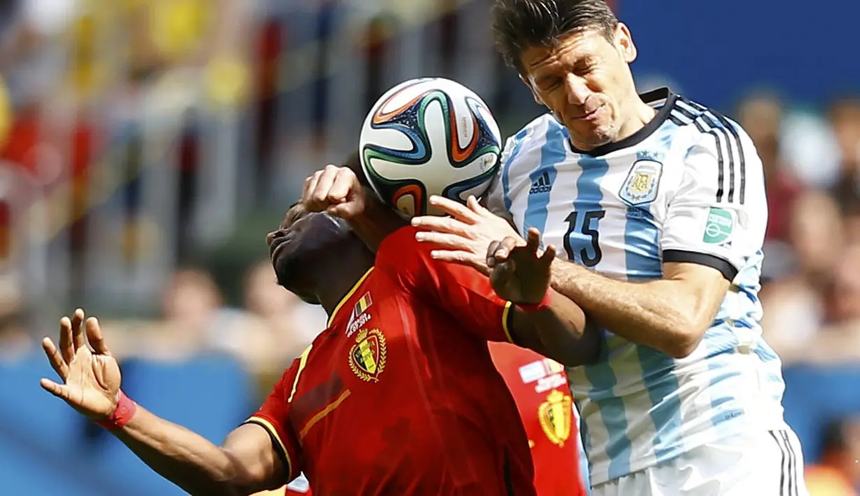 Penyerang Timnas Belgia, Divock Origi (kiri), berebut bola dengan pemain belakang Argentina, Martin Demichelis, di laga perempat final Piala Dunia 2014 di Stadion Nasional Brasilia, (5/7/2014). (REUTERS/Dominic Ebenbichler) 