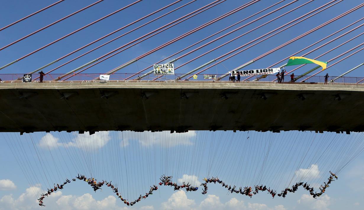 Ratusan orang melompat menggunakan tali dari jembatan yang memiliki ketinggian 30 meter di Hortolandia, Brasil, Minggu (10/4). Sebanyak 149 orang mencoba membuat rekor dunia dengan melompat bersama dari atas jembatan. (REUTERS/Paulo Whitaker)