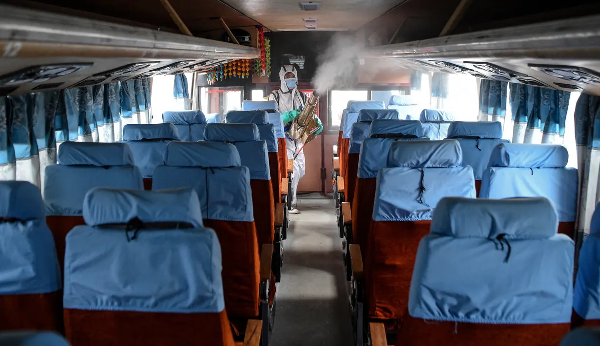 Seorang pekerja yang mengenakan Alat Pelindung Diri (APD) menyemprotkan disinfektan pada bus di Kathmandu, Kamis (17/9/2020). Pemerintah Nepal melonggarkan pembatasan yang diberlakukan sebagai tindakan pencegahan terhadap virus corona pada transportasi umum jarak jauh. (PRAKASH MATHEMA/AFP)