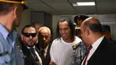 Mantan pemain Barcelona asal Brasil, Ronaldinho (tengah) tiba di Asuncion's Justice Palace untuk bersaksi tentang masuknya dia yang tidak teratur ke negara itu, di Asuncion, pada 6 Maret 2020. Ronaldinho mengumumkan dirinya positif Covid-19 pada Minggu (25/10/2020) malam WIB. (AFP/Norberto Duarte)