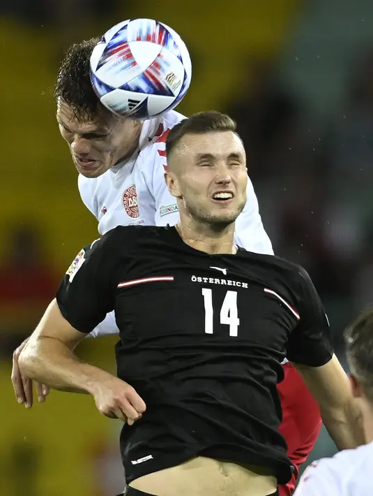 Bek Denmark, Jannik Vestergaard berebut bola dengan pemain Austria, Sasa Kalajdzic pada pertandingan UEFA Nations League di Stadion Ernst Happel di Wina, Austria, Selasa (7/6/2022). Denmark menang tipis atas Austria 2-1. (AP Photo/Andreas Schaad)