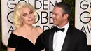 Lady Gaga ditemani Taylor Kinney menghadiri acara Golden Globes 2016 di Beverly Hilton Hotel, California, Minggu (10/1). Kompak mengenakan gaun bernuansa hitam, sang Mother Monster menggandeng mesra sang tunangan. (Jason Merritt/Getty Images/AFP)