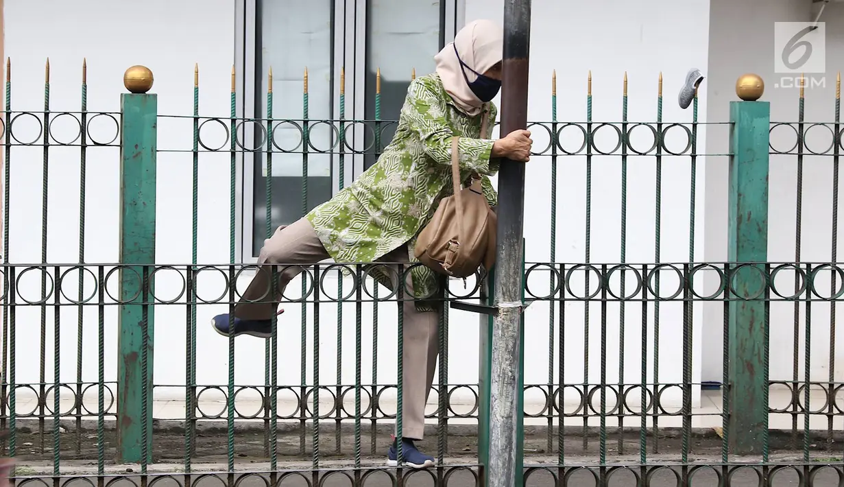 Penumpang melompati pagar pembatas untuk keluar dari Stasiun Cikini di Jakarta, Jumat (22/3). Jauhnya akses pintu masuk dan keluar stasiun menyebabkan sebagian orang mempersingkat waktu dengan melompat pagar pembatas. (Liputan6.com/Immanuel Antonius)