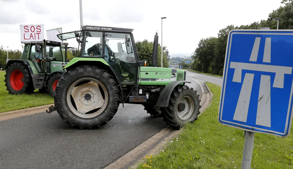 Sebuah traktor milik peternak sapi perah memblokade jalan tol atau jalan bebas hambatan saat melakukan aksi protes di Battice, Belgia, Kamis (30/7/2015). Aksi protes tersebut berkaitan dengan rendahnya harga jual susu. (REUTERS/Francois Lenoir)
